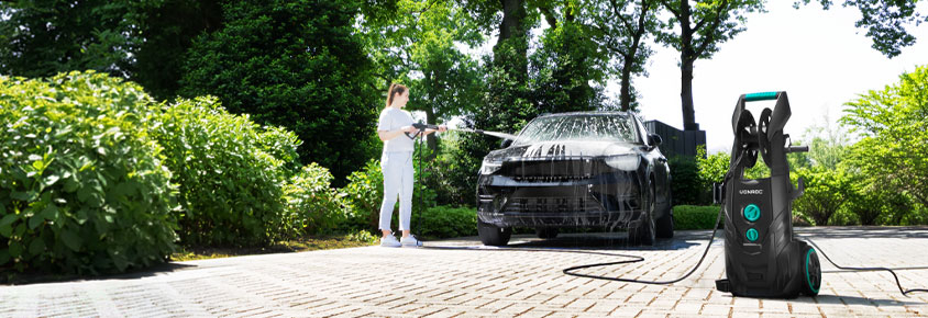 Una mujer limpia un coche con la hidrolimpiadora VONROC V25.